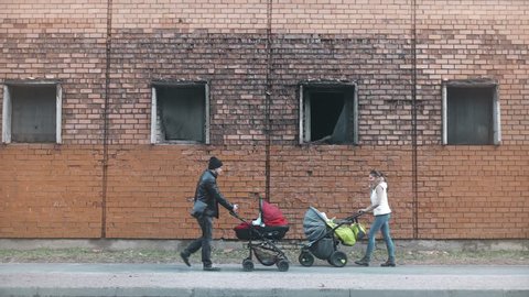 man and woman walking with children in prams going to meet each other