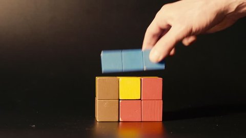 Man's hand picking 3D tetris close up