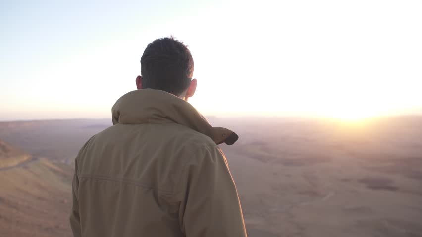 Man looking at the view of the desert under the morning sunlight