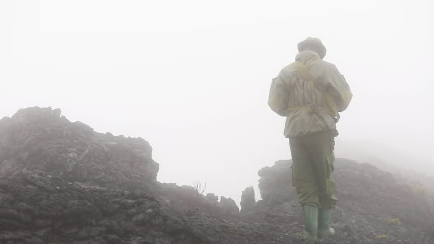 Park ranger in heavy fog walking around volcano crater and disappears in thick fog.