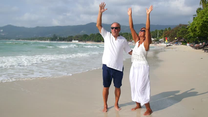 Happy Senior Couple in White Clothes on Vacation at Beach