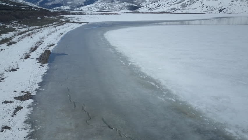 Aerial of Early spring ice melting off lake. Late winter snow on landscape of central Utah. Reservoir lake.
