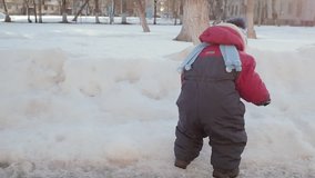 Little boy playing with snow on his gloves. Video full hd.