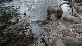 Camera moves from right to left and shoots as the river sweeps stones along its course. Video full hd.