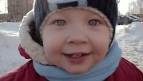 Small child with expressive eyes looks at the camera and smiles. Outdoors video full hd.