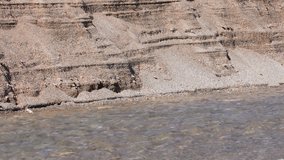 Sand on the river bank next to a river erodes and falls into the river