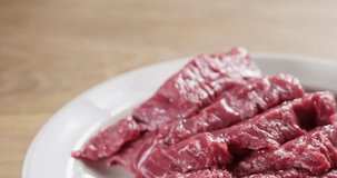 closeup pan of fresh sliced raw beef in plate on kitchen table, 4k prores footage