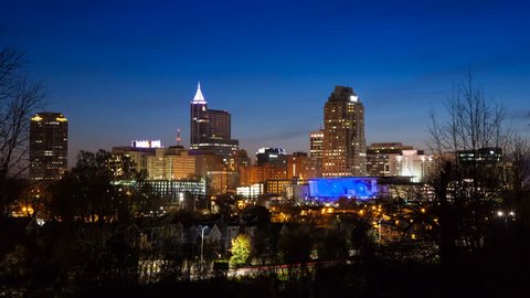 Sunrise Timelapse Over Raleigh NC City Skyline with Lit Building Exteriors in front of a Blue Sky Moving from Night to Day 