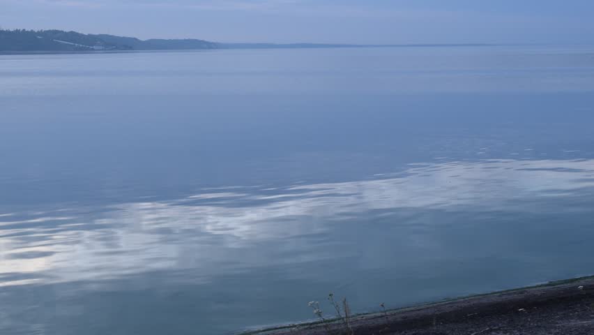 Young man skipping stones on lake or river at dusk in the evening