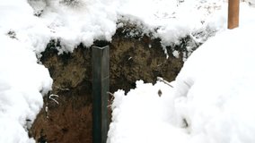 Time lapse of pounding an iron angle bar profile with big sledge hammer into earth in winter to make earthing. The L-bar quickly goes into soil.