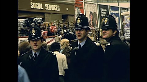 LONDON, UNITED KINGDOM - CIRCA 1979: typical english policemen bobby of London in historic street market Petticoat Lane Market. Historic restored footage on 1970s. 