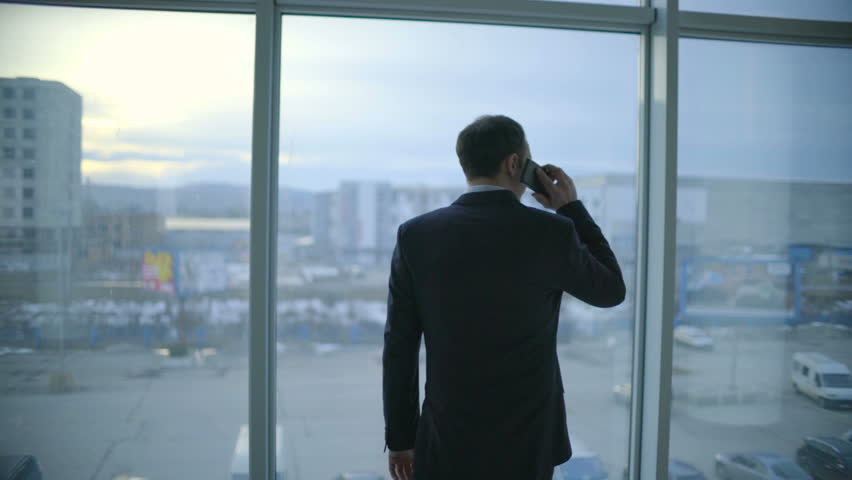 The businessman walk and phone near the panoramic window. Slow motion | Shutterstock HD Video #25232618