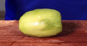 Video footage of woman hands cutting a fresh kiwi fruit on the chopping board. Professional shot in 4K resolution