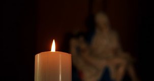 JAKARTA, March 22, 2017: Video footage of a candle flame shining in church with a sculpture of Pieta on the background. Professional shot in 4K resolution.