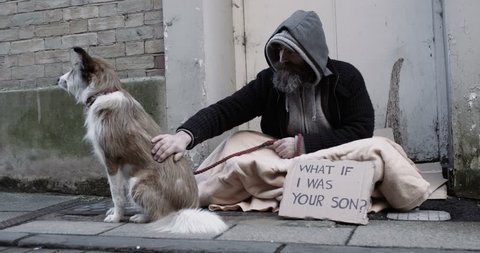 4k, Homeless man and his dog with a cardboard sign sitting on a sidewalk. Slow motion.