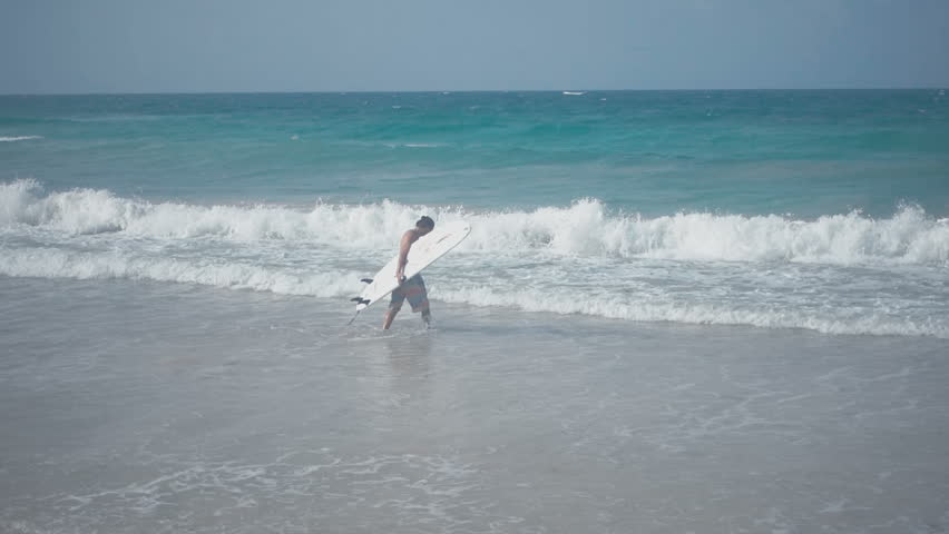 Young surfer enters the water in the daytime