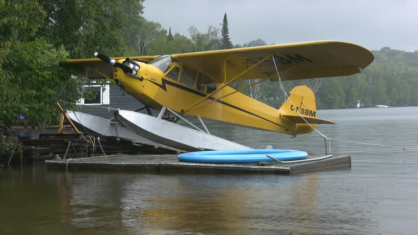 A yellow seaplane docked at a rainy lake. North Ontario, Canada.