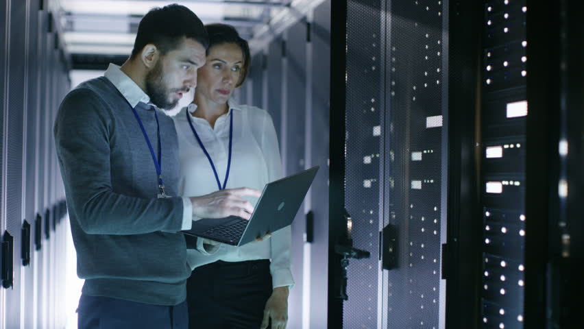 Male and Female Server Engineers Work on a Laptop in Data Center. He Opens Rack Server Cabinet. Shot on RED EPIC-W 8K Helium Cinema Camera. Royalty-Free Stock Footage #25243076