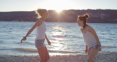Beautiful young woman hugging teenage girl friend emotional engagement on vacation at sunset magic hour