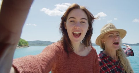 Attractive girl friends taking selfie photograph with smartphone smiling two young woman enjoying enjoying vacation travel adventure POV