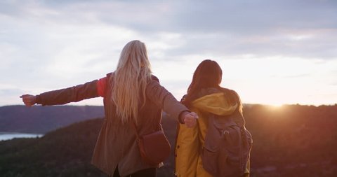 Beautiful women arms raised enjoying sunset landscape travel adventure tow girls best friends celebrating nature