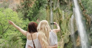 Attractive girl friends taking selfie photograph with smartphone woman enjoying swimming in waterfall nature background view enjoying vacation travel adventure