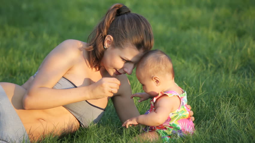 young girl playing with her little child on the green field