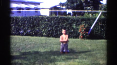 MINNESOTA 1959: the boy was kneel down in the garden and laugh very much to play in other type in long way to in grad
