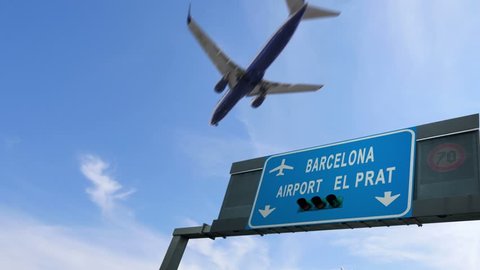plane flying above barcelona airport signboard