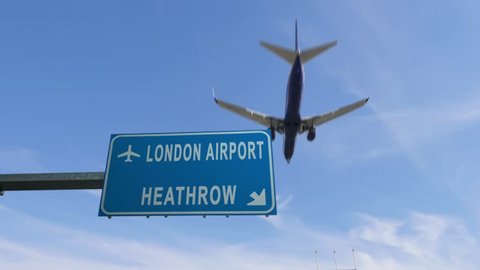london heathrow airport sign airplane passing overhead