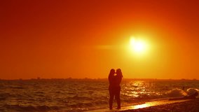 Silhouette of young couple kissing on the summer beach at sunset