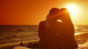 Young couple kissing on the summer beach at sunset