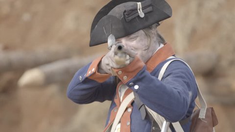 VIRGINIA - OCTOBER 2016 - American Revolution era Continental Patriot Soldier. Re-enactors, reenactment.  Firing Brown Bess musket gun with black powder and lead bullets in earthen fort in battle. 