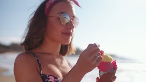 Young brunette hipster girl enjoying ice cream at beach in the summer