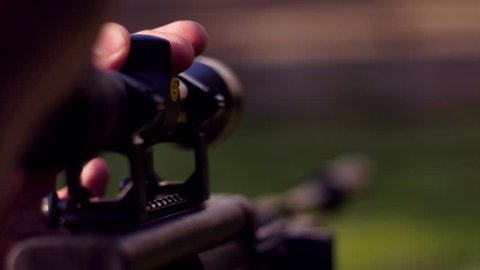 Hunter adjusting snipe rifle scope