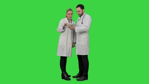 Pretty female nurse and handsome doctor with stethoscope using digital tablet on a Green Screen, Chroma Key.
