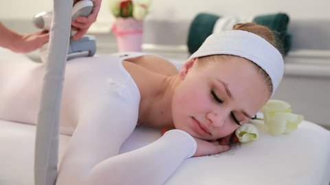 Woman is in the process at the clinic lipomassage. LPG massage in the beauty center. Woman lying on the bed in a spa salon enjoying and receiving lipo massage procedure. Spa treatments, beauty center