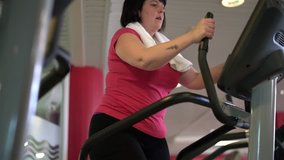 Overweight woman at the gym doing cardio exercises on bike