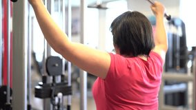 Overweight woman at the gym lifting weight