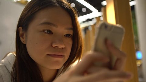 4K Beautiful Asian Woman Waiting on the Restaurant is a good time to get some work done on your phone device, using smartphone for cheks her e-mail and writting text, as she waits.-Dan