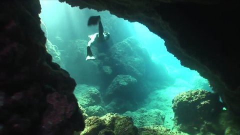 free diver apnea underwater in cave around rocks holding breath