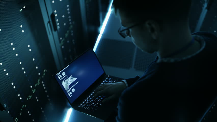 High Angle Shot of IT Specialist Holding Notebook and Working on it. He's Employee of Big Ultramodern Data Center. Shot on RED EPIC-W 8K Helium Cinema Camera. Royalty-Free Stock Footage #25323422