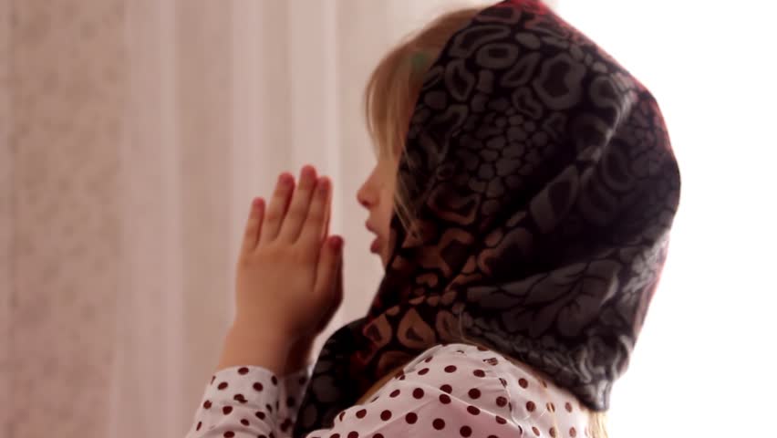 Cute little girl in a headscarf, praying at home in front of the icon. Concept, Russian Orthodox little girl, Christianity.