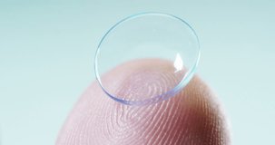 Macro shot of a finger holding a contact lens technology with a chip to see better in both eyes and increase diopters. Concept: eye examination, optical, immersive technology