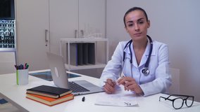 Friendly adult doctor looking at the camera and talking. Woman md wearing in white coat giving advice people about health care or healthy lifestyle.