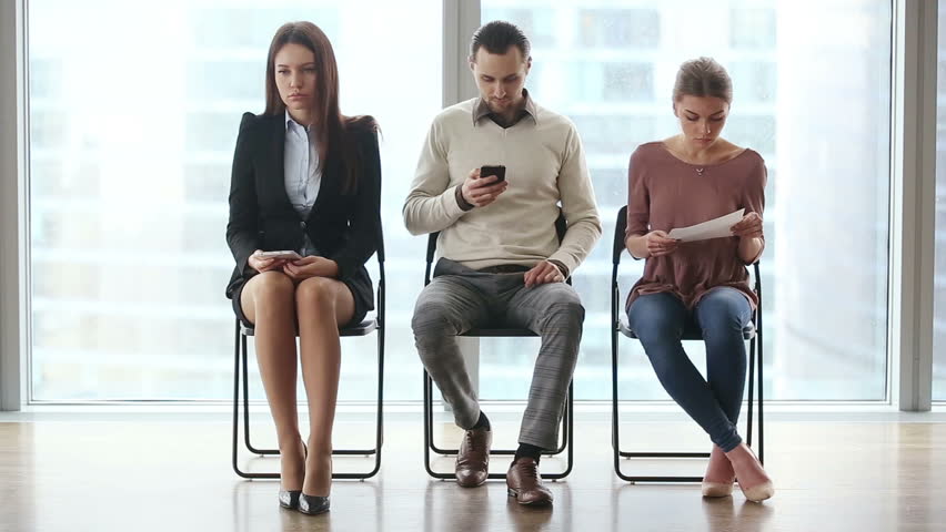 Group of three young casual people candidates sitting on chairs in modern office lobby, waiting too long for job interview, using technology devices, feeling nervous. Full length. Job search concept Royalty-Free Stock Footage #25331186