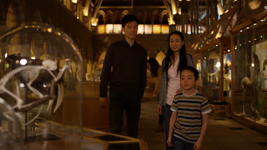 4K Asian family in natural history museum looking at a skeleton inside glass jar