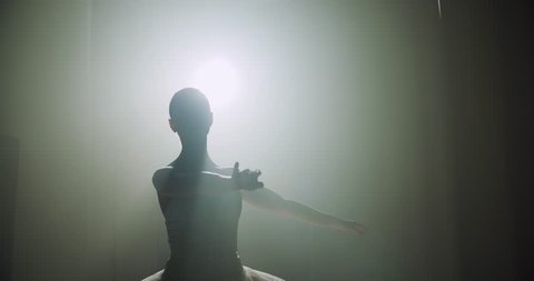 Ballerina dances on stage, close-up with magic light and smoke on the background, slow motion