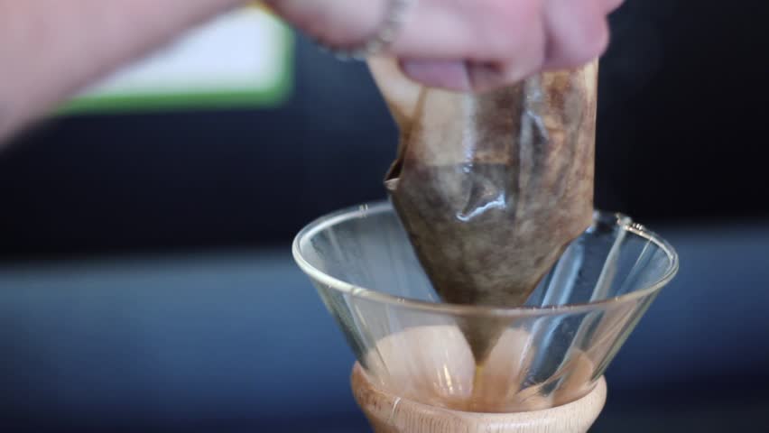 Purist kemeks. Barista takes out the filter with the coffee cake from the glass bulb.
