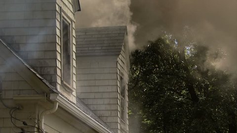 Smoke pouring out of dormers on roof of house